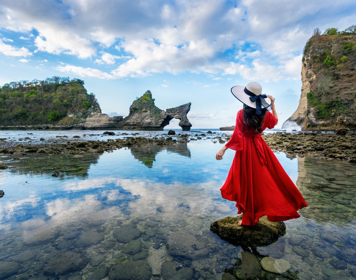 Woman standing on the rock at Atuh beach, Nusa penida island in Woman standing on the rock at Atuh beach, Nusa penida island in Bali, Indonesia.